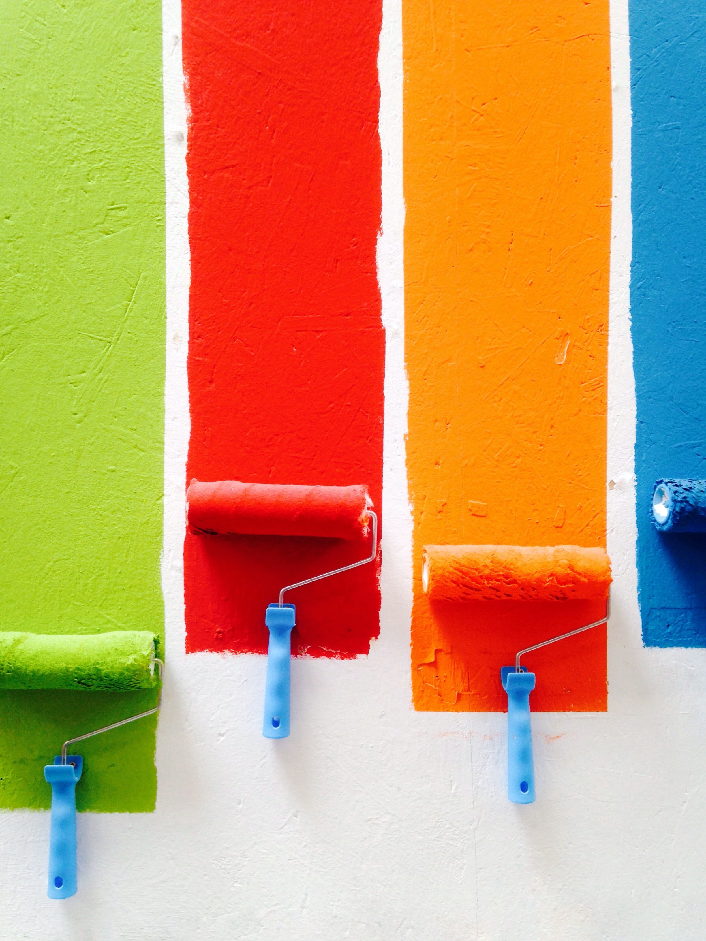 Color Psychology - Paint rollers painting in green, red, yellow and blue.