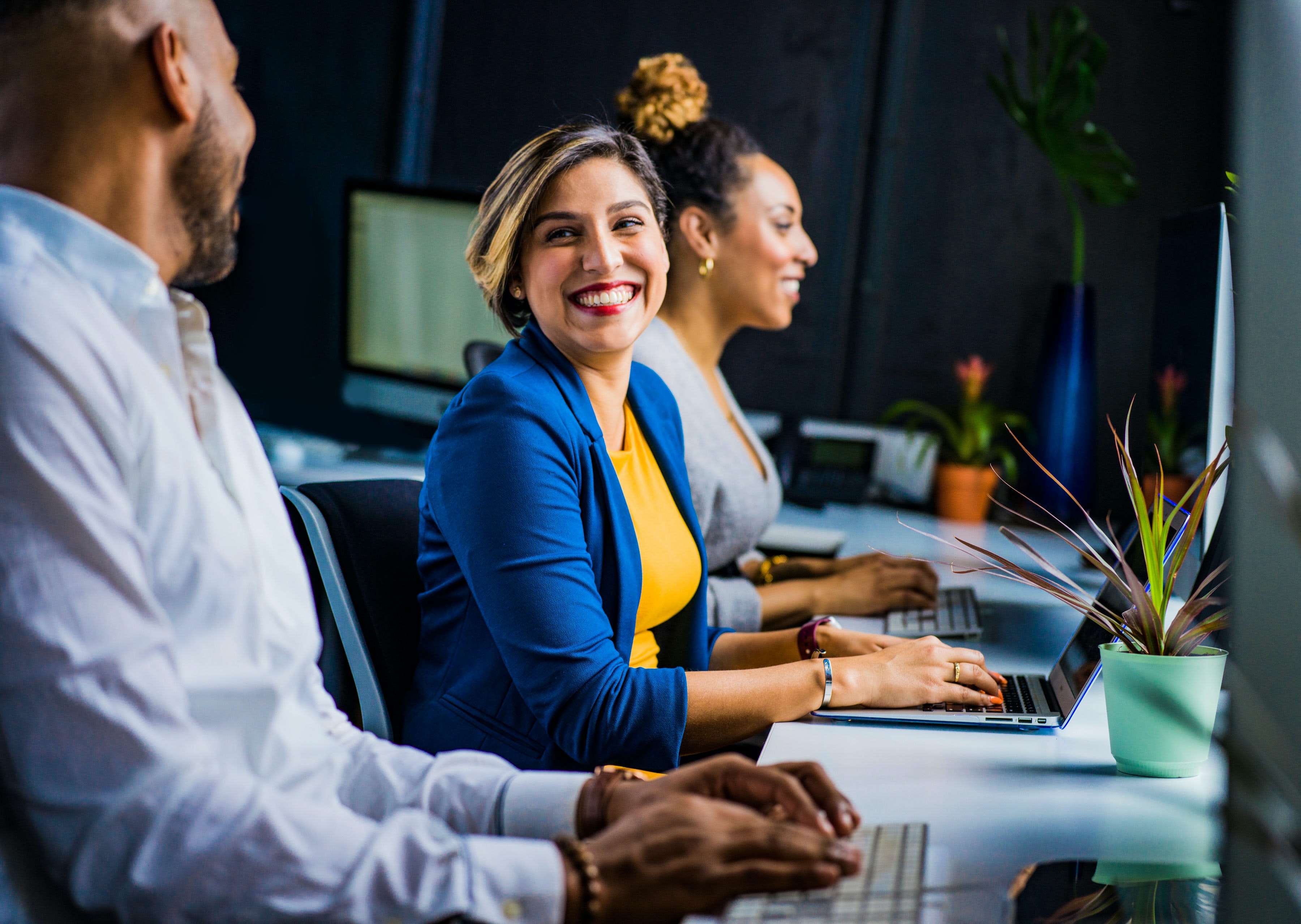 Customer-Centric Approach - 2 female workers and a male smiling at the office.